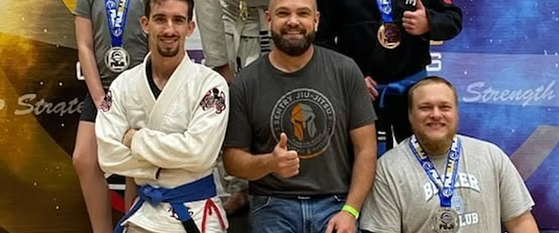 Sentry Jiu-Jitsu coach and students with medals at a competition