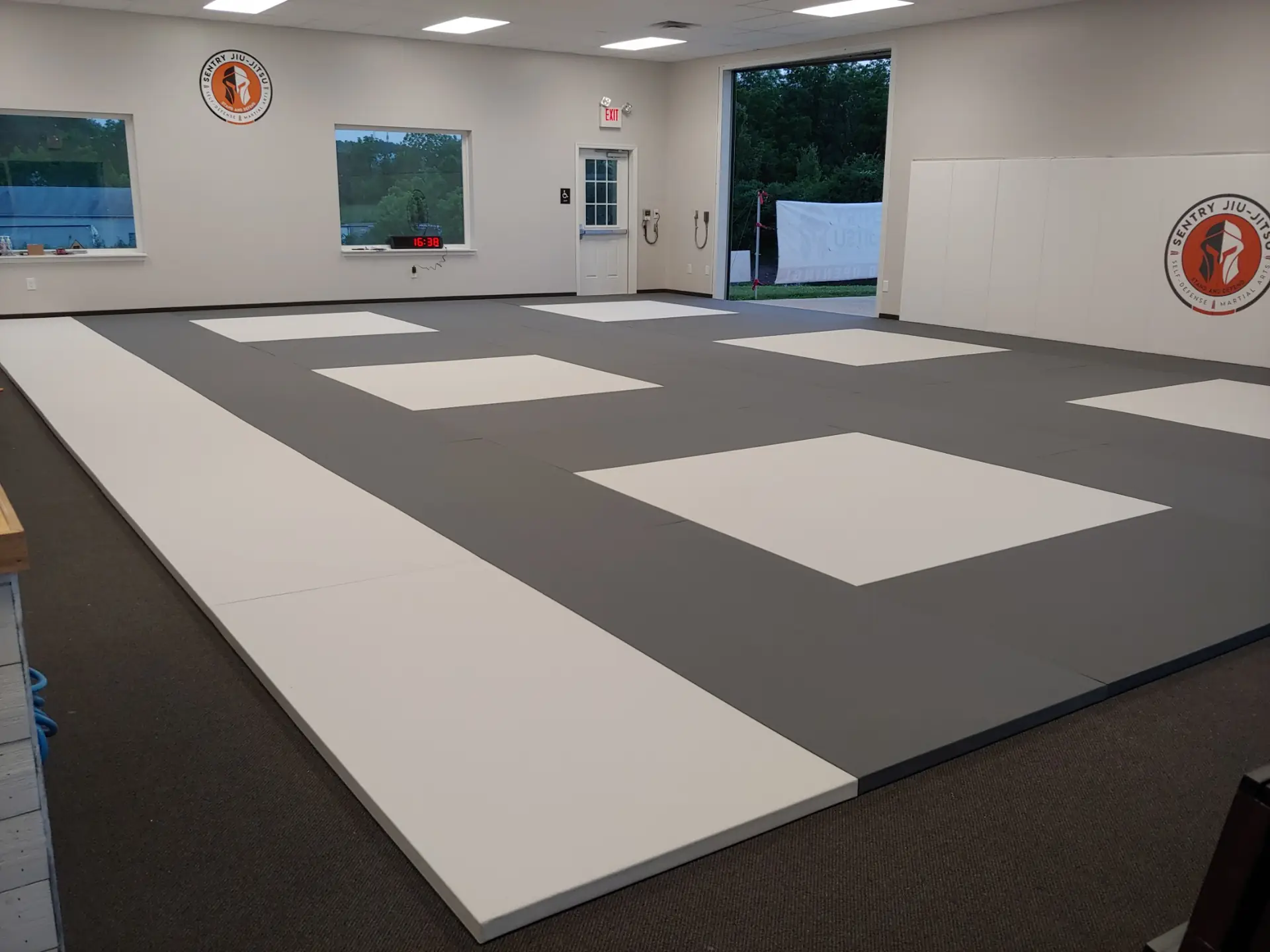 The clean, fully-matted training floor at Sentry Jiu-Jitsu in Gilbertsville, with the Sentry logo on the wall